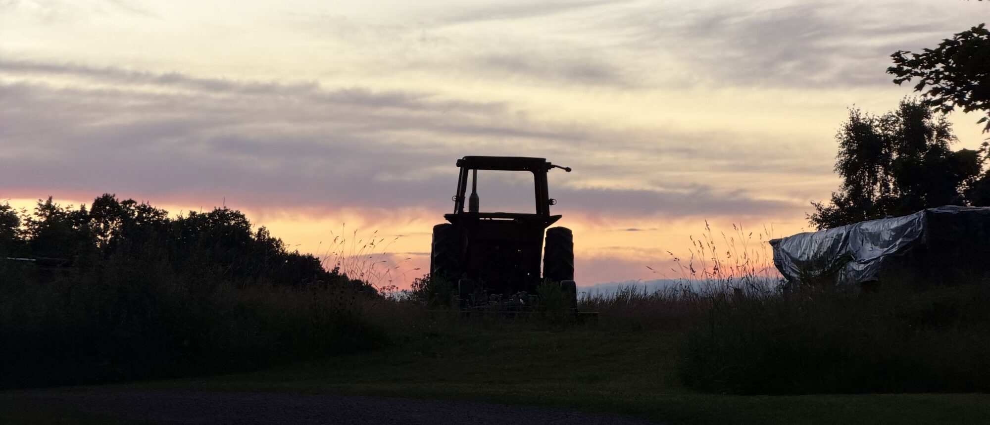 An old tractor at rest against the dusk sky at Gullö Gård, Finland